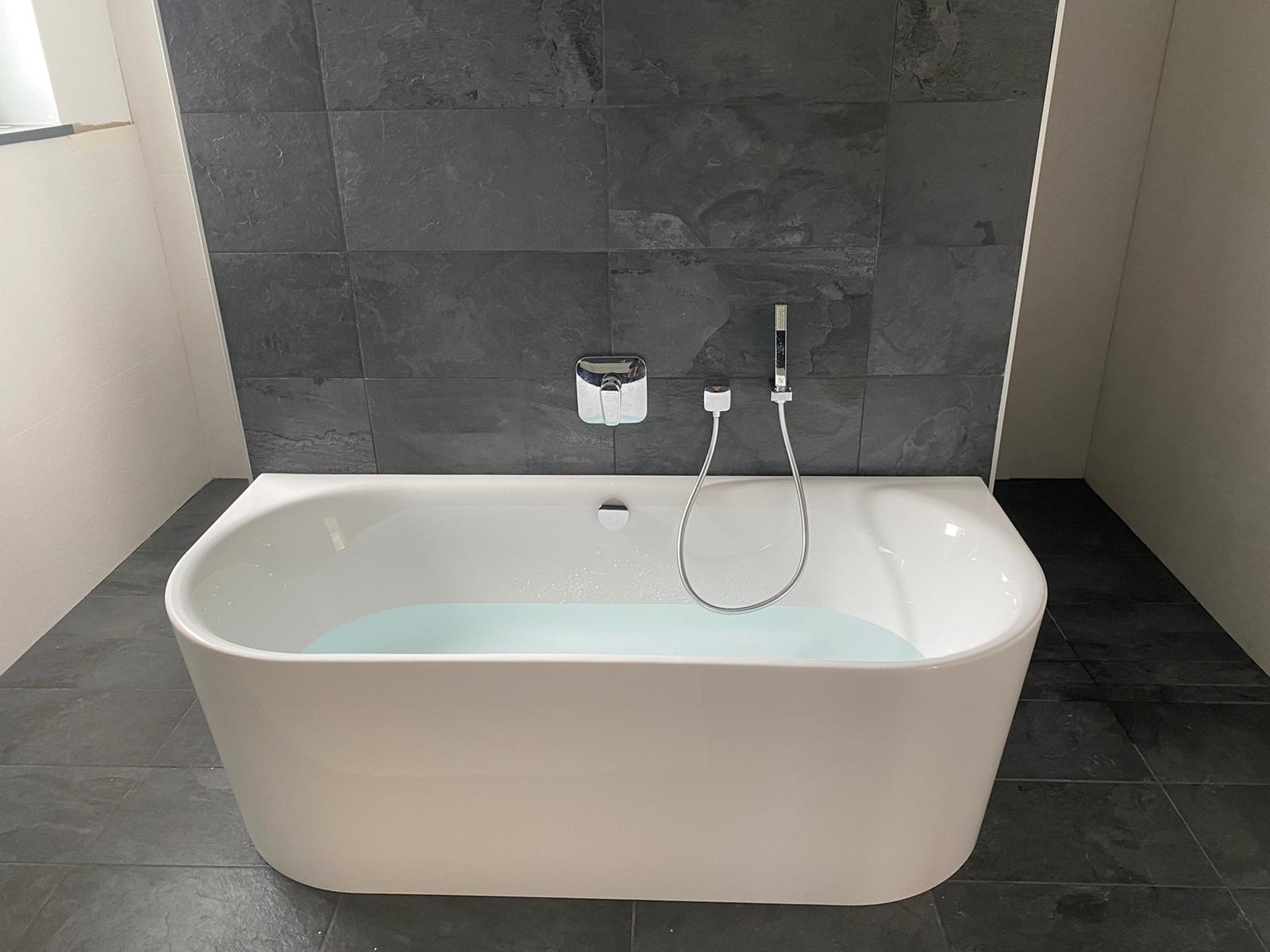Bad mit freistehender Wanne vor Schieferwand