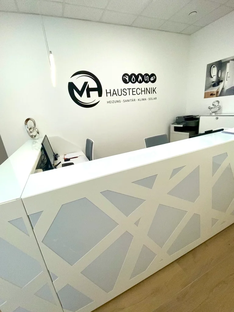 Empfangstheke im Büro der MH Haustechnik mit Firmenlogo an der Wand
