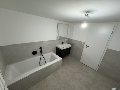 Bad mit Badewanne und schwarzem Waschtischunterschrank